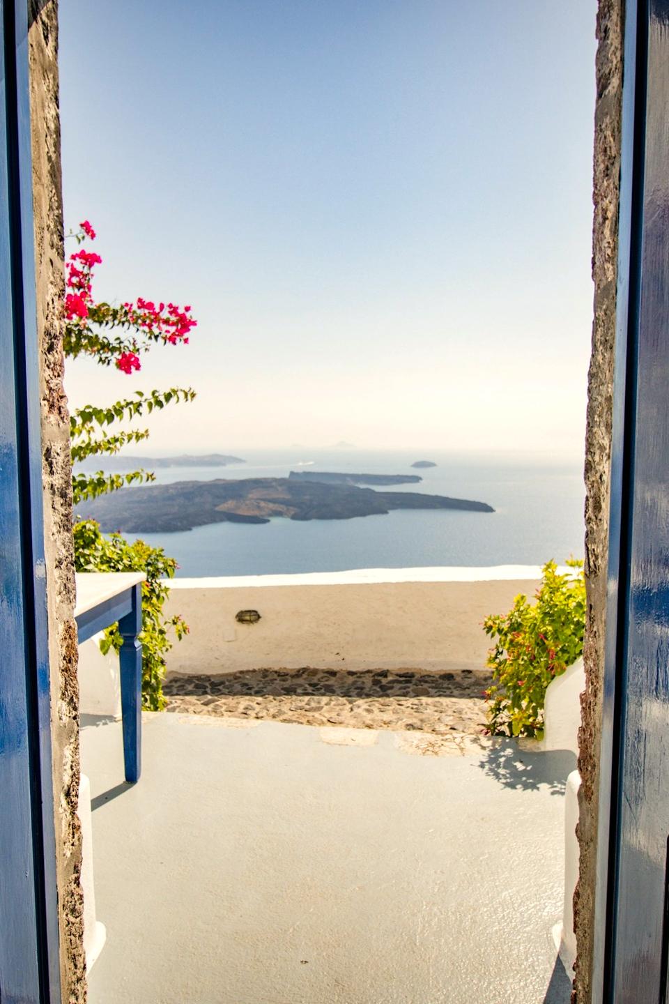 Open blue double door onto white houses and the sea