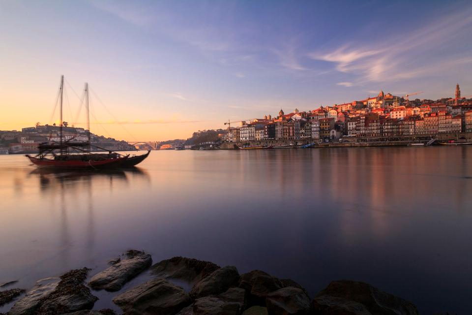 The Ribeira district of Porto across the Douro river at sunset, with a traditional rabelo boat